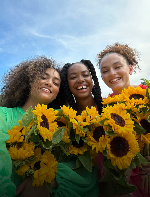 Ευκρινής και ζωηρή selfie τριών ατόμων που κρατούν λουλούδια.